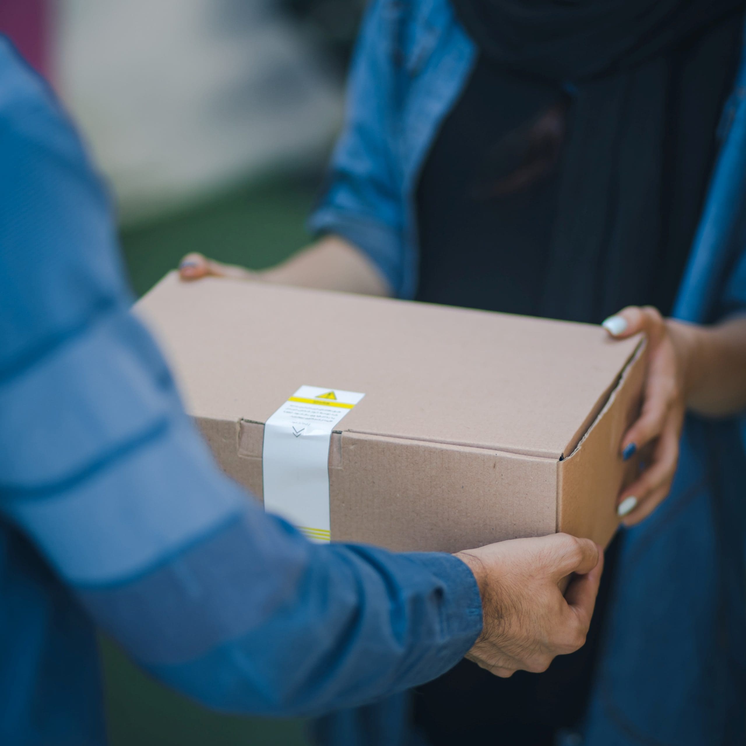 Two people passing a moving box